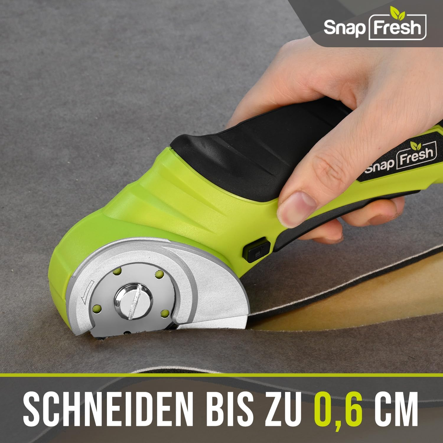 Eine Hand hält einen grün-schwarzen elektrischen Schneider, der Stoff schneidet. Der Text lautet 'SCHNEIDEN BIS ZU 0,6 CM'.