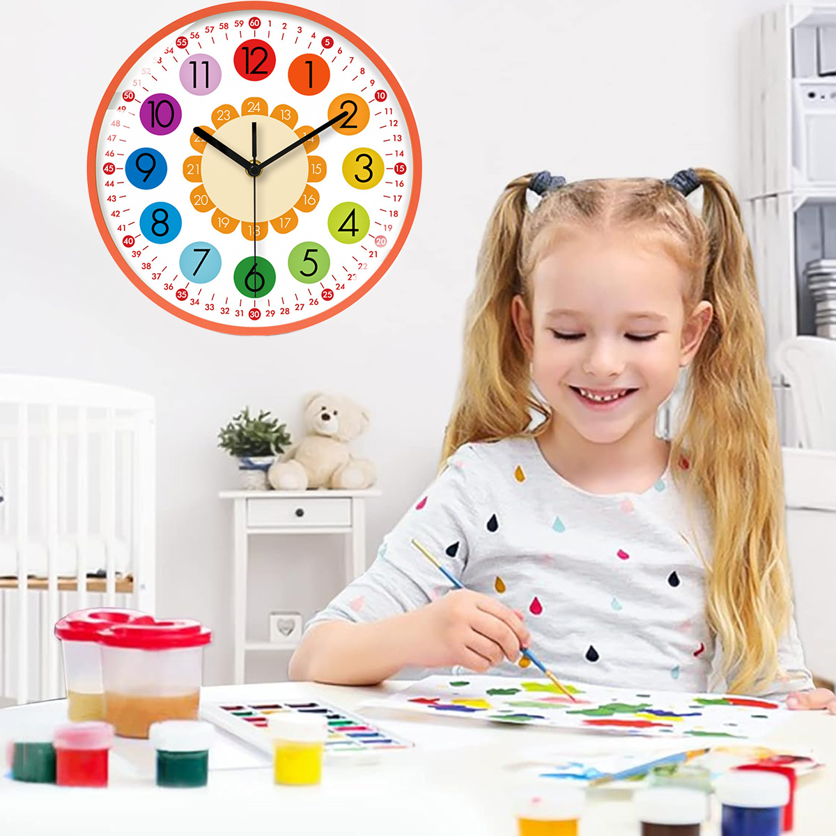 Ein Mädchen malt am Tisch, darüber hängt eine Uhr. Farben und ein Teddybär stehen auf dem Tisch. Die Uhr zeigt 1:15.