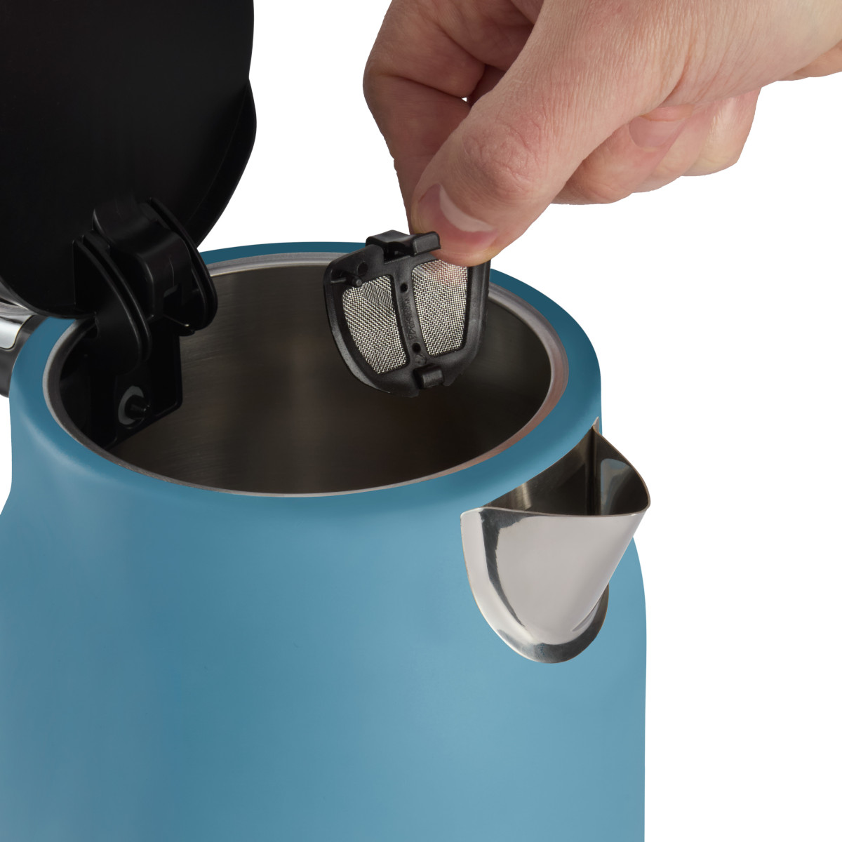 Eine Hand legt einen Tee-Infuser in einen blauen Wasserkocher. Der Deckel des Wasserkochers ist offen. Der Hintergrund ist weiß.