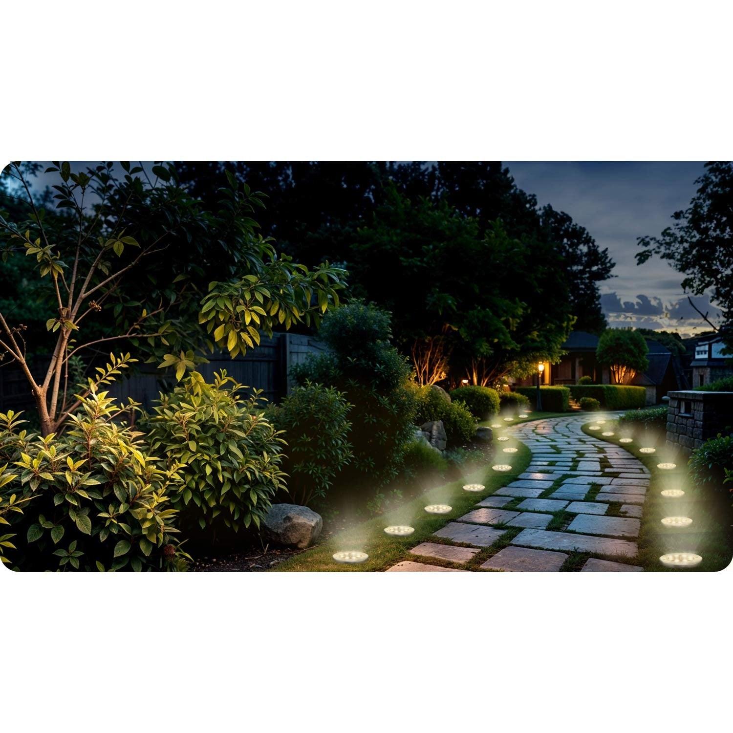 Un sendero de piedra iluminado con luces de suelo serpentea por un jardín al anochecer. La vegetación y los árboles bordean el camino.