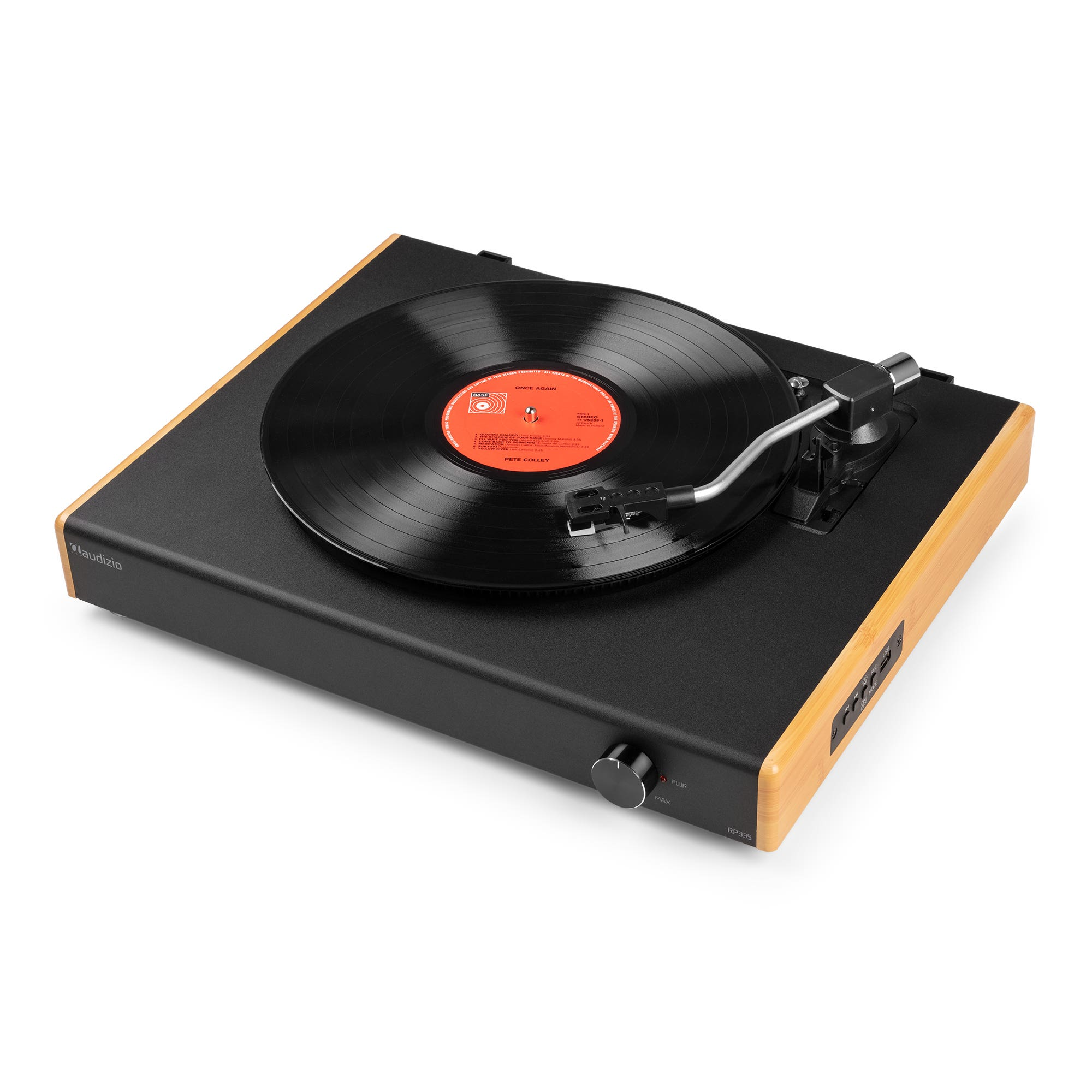 Un tocadiscos con un disco negro en reproducción. El tocadiscos es negro con laterales de madera, sobre una superficie blanca.