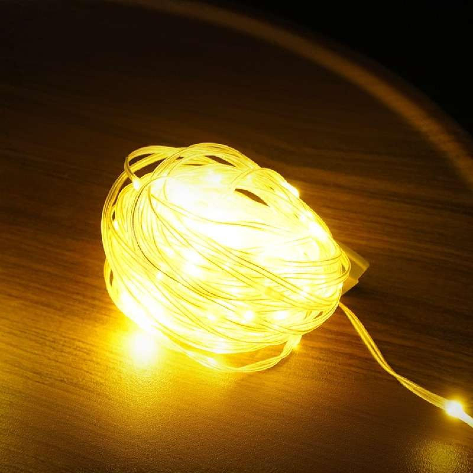 Nahaufnahme einer Kugel aus gelben Lichterketten auf einer Holzoberfläche. Einige Lichter sind an, andere aus.