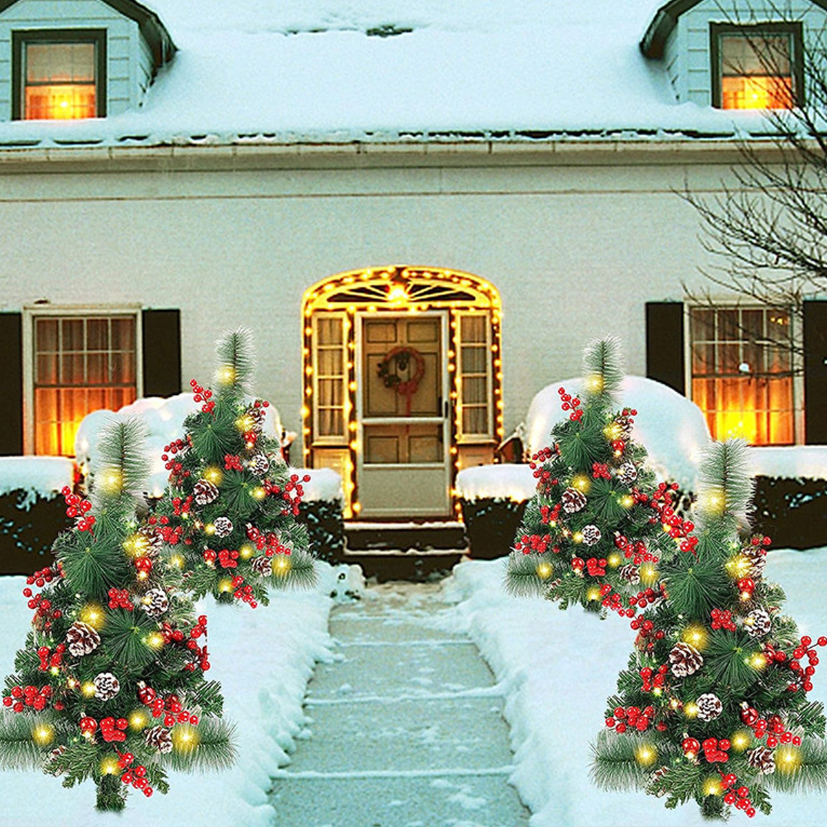 Ein schneebedecktes Haus mit Weihnachtsdekorationen. Kleine dekorierte Bäume säumen den Schneeweg zur Tür. Fenster haben Lichter.