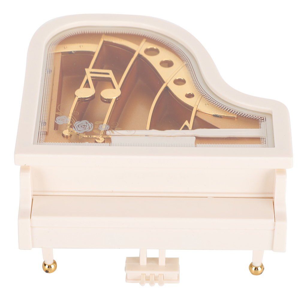 Eine weiße Klavier-Spieluhr. Sie hat goldene Noten im Inneren, eine Klaviatur und goldene Akzente an den Beinen.