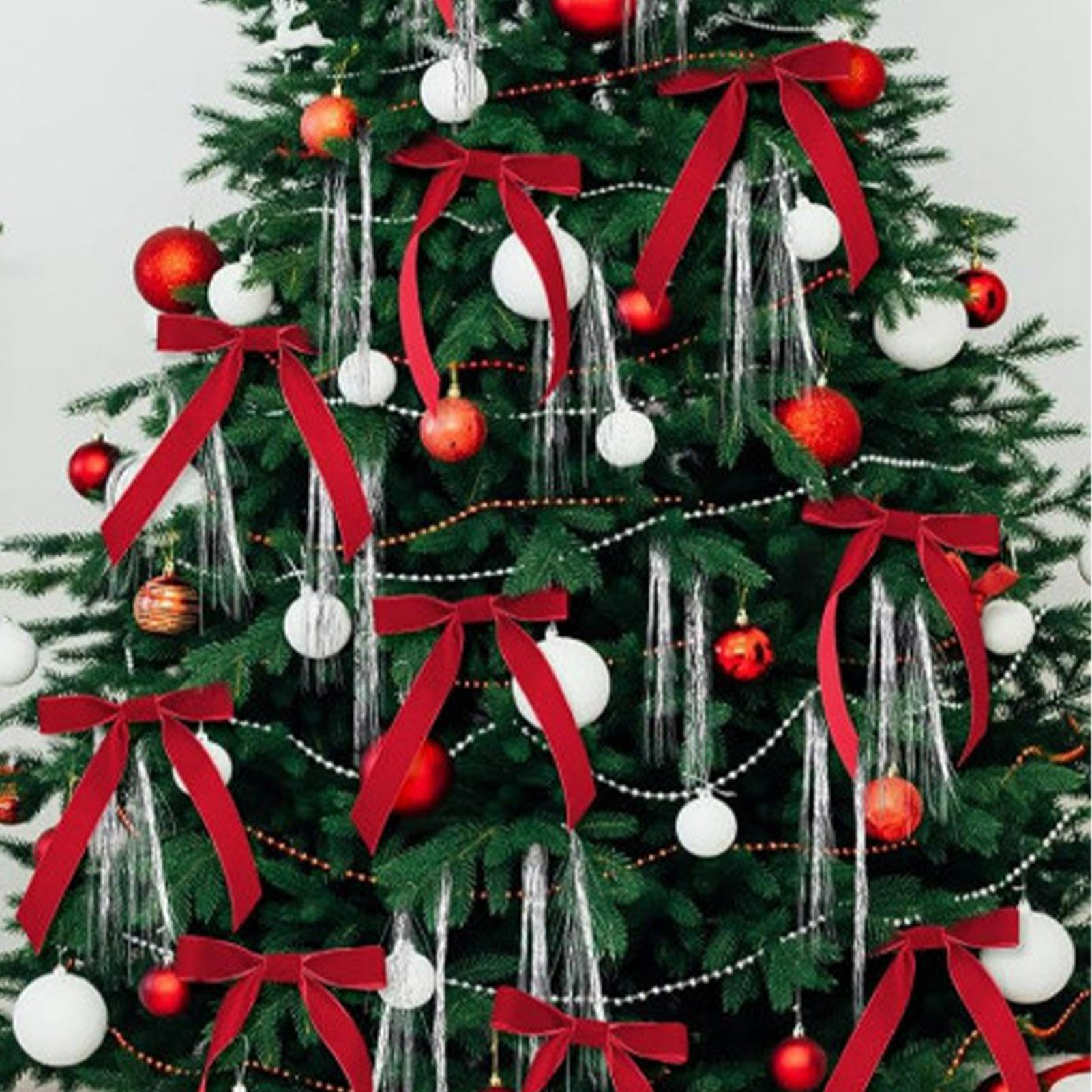 Ein geschmückter Weihnachtsbaum mit roten Schleifen, Ornamenten und silbernem Lametta. Weiße und rote Ornamente sind sichtbar.