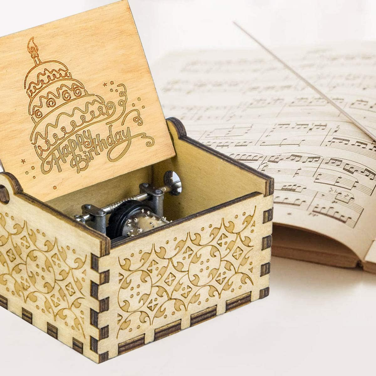 Holz-Musikbox mit Geburtstagskuchen-Gravur. Geöffnet, Mechanismus sichtbar. Noten im Hintergrund.