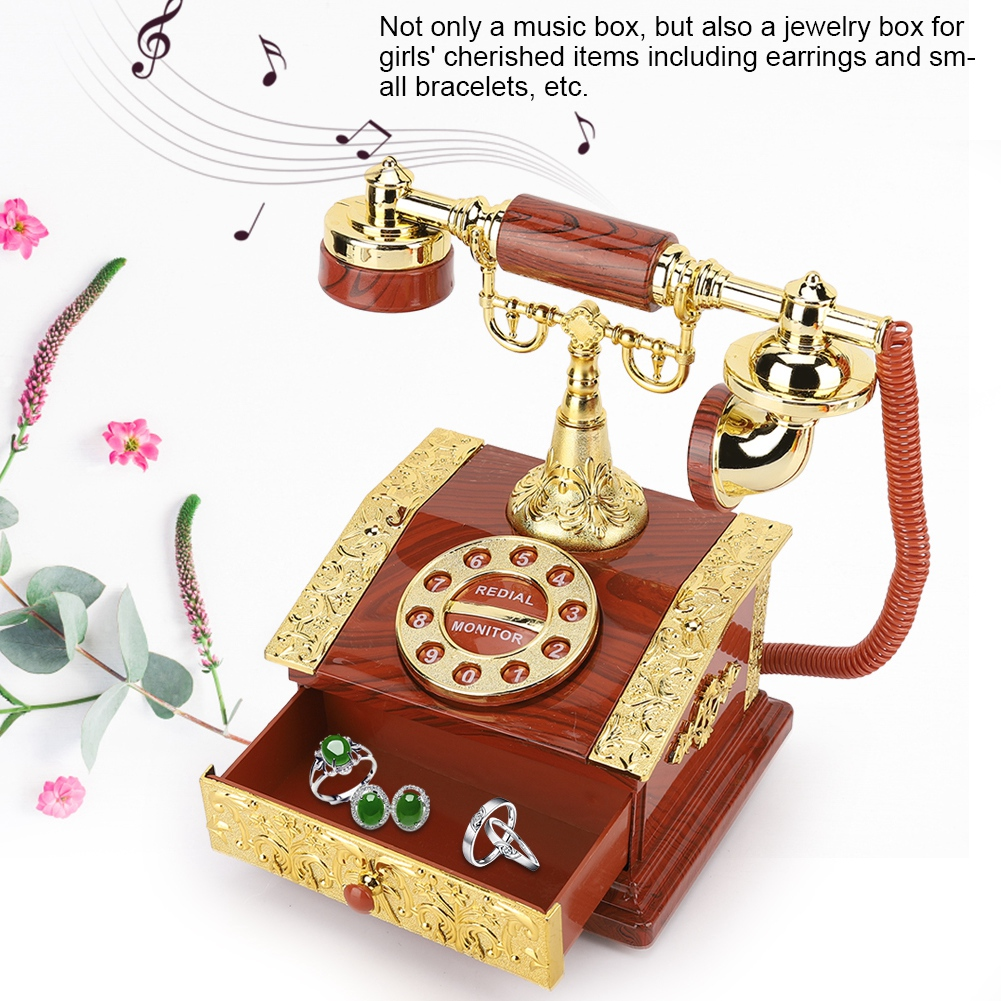 Eine dekorative Spieluhr in Form eines Vintage-Telefons, mit Schmuck in einer Schublade. Blumen und Noten im Hintergrund.