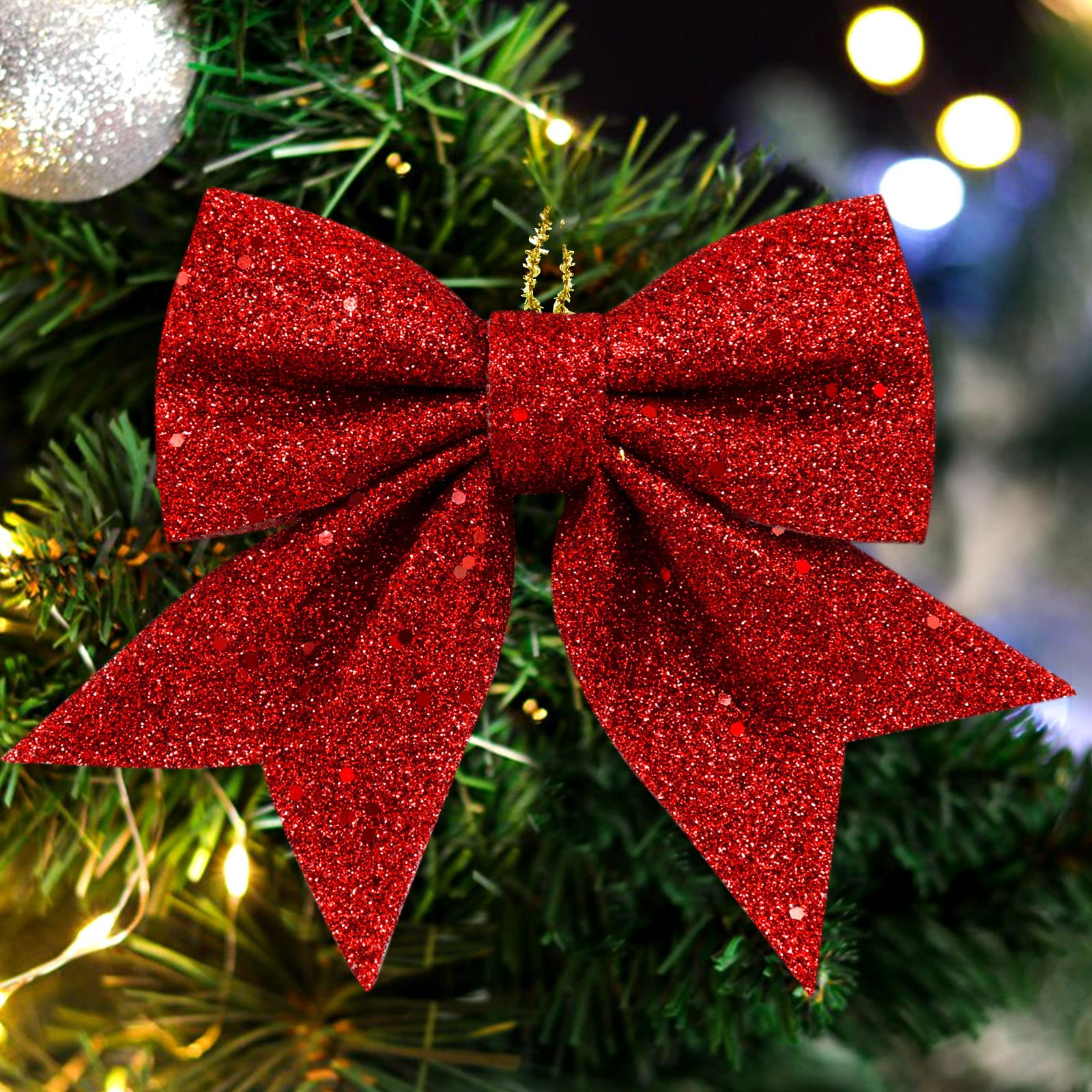 Nahaufnahme einer roten Glitzer-Schleife auf einem Weihnachtsbaum. Der Hintergrund hat Lichter und eine silberne Verzierung.