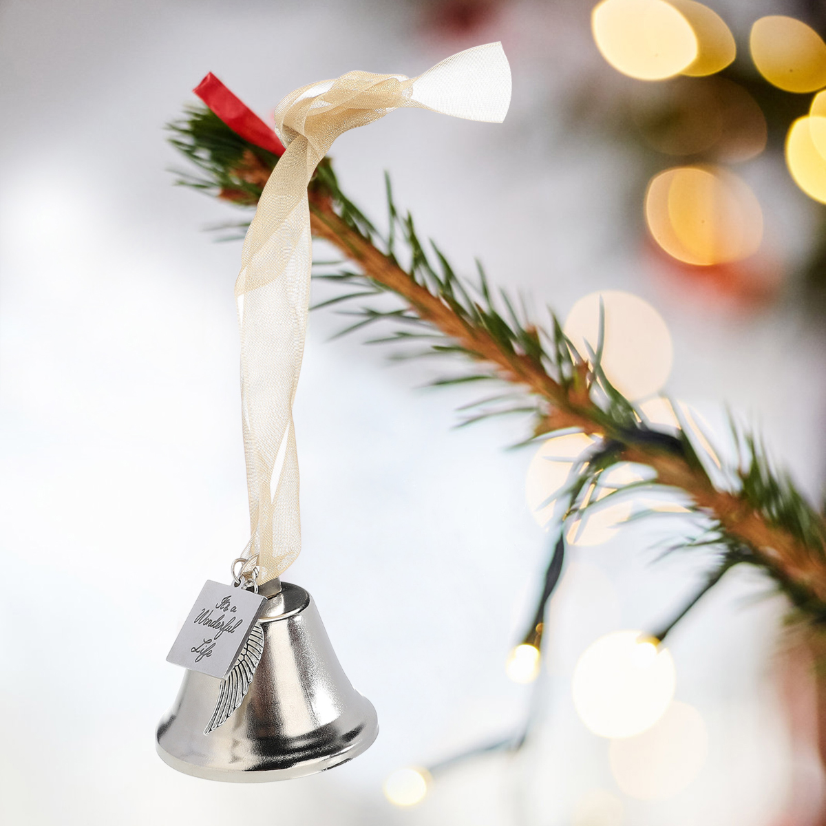 Ein silberner Glockenornament hängt an einem Weihnachtsbaumzweig. Es hat ein Band und ein Etikett mit der Aufschrift "It's a Wonderful Life."