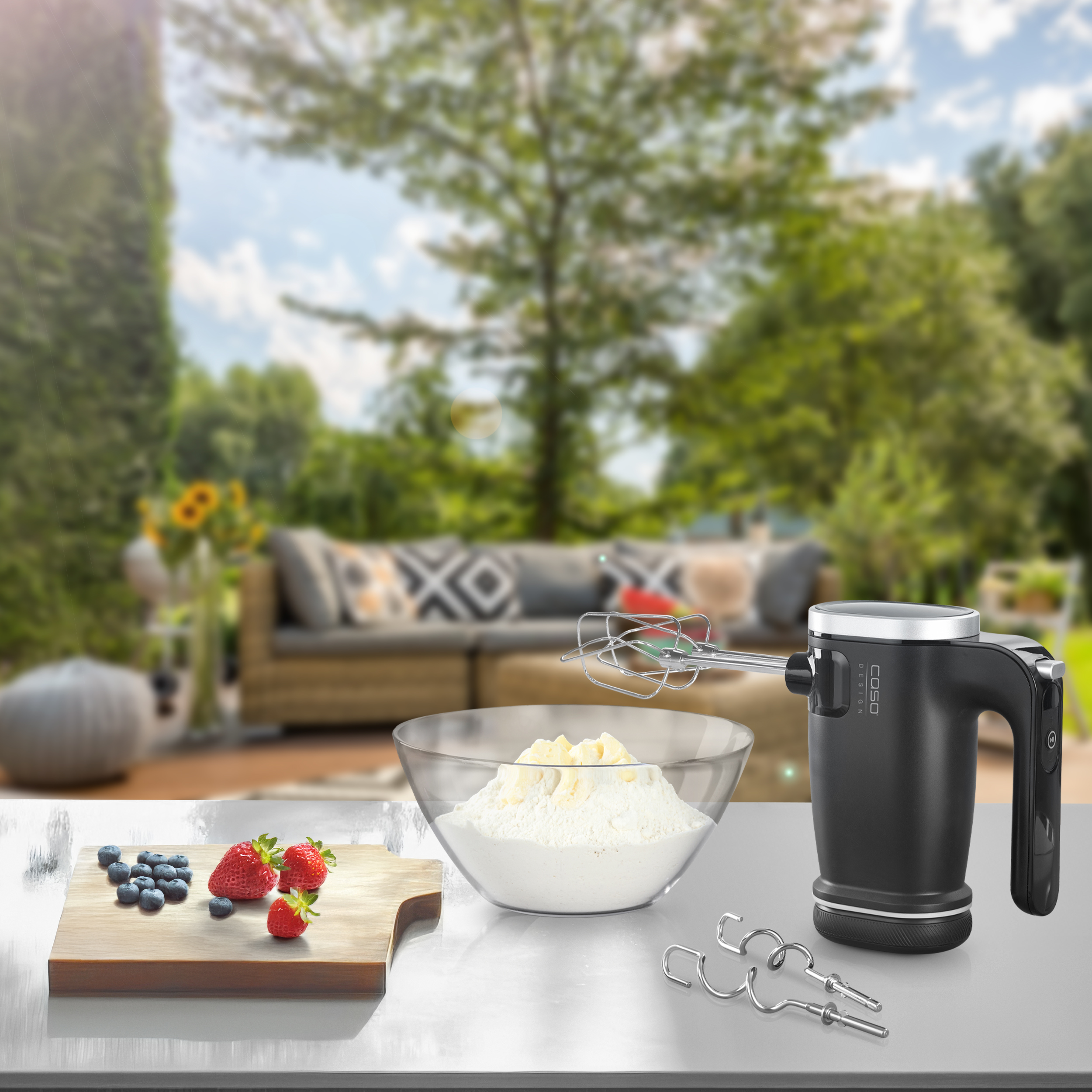 Una scena di cucina con ingredienti e un mixer. Mirtilli, fragole, farina e un mixer nero sono visibili.