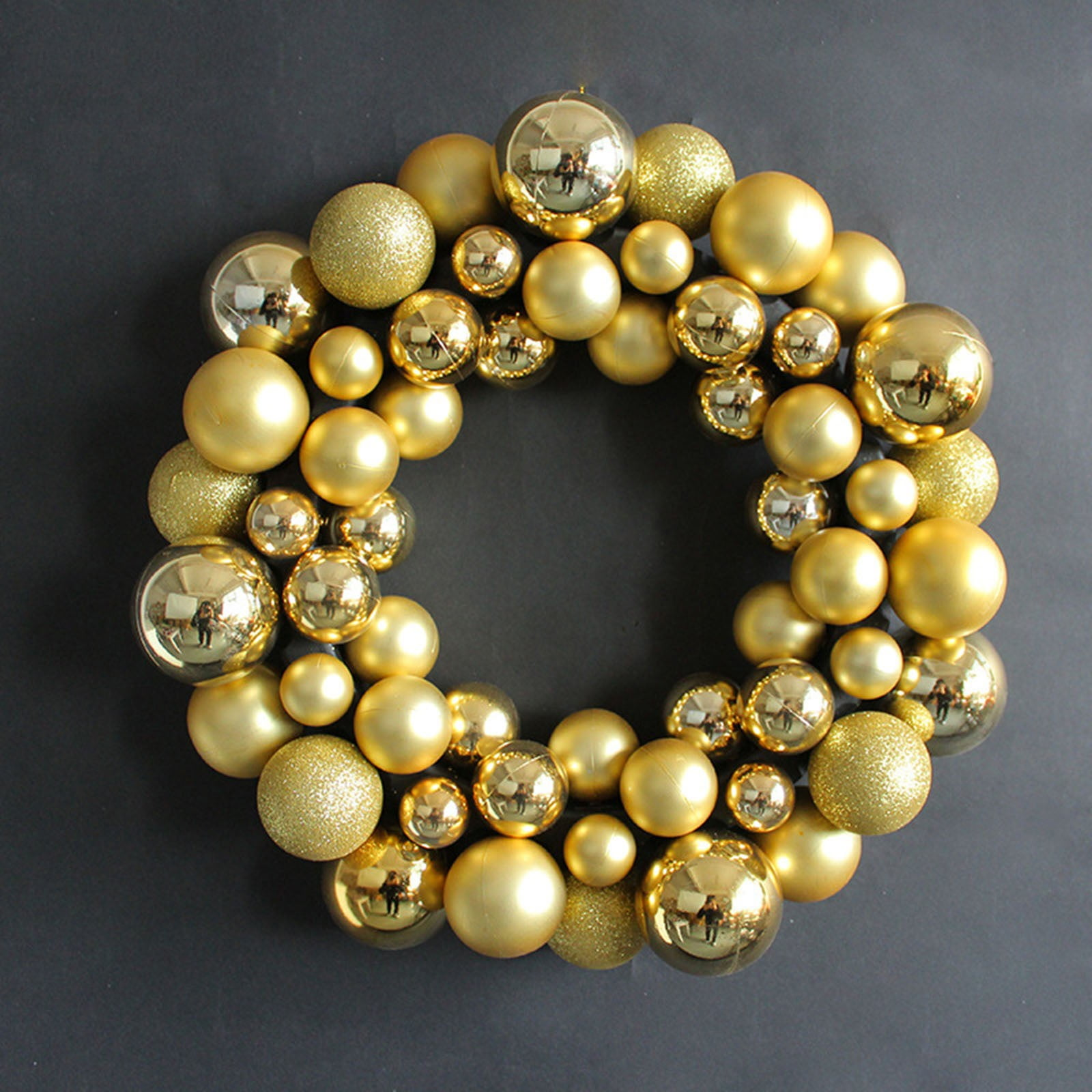 Ein goldener Weihnachtskranz aus glänzenden und glitzernden Ornamenten vor dunklem Hintergrund.