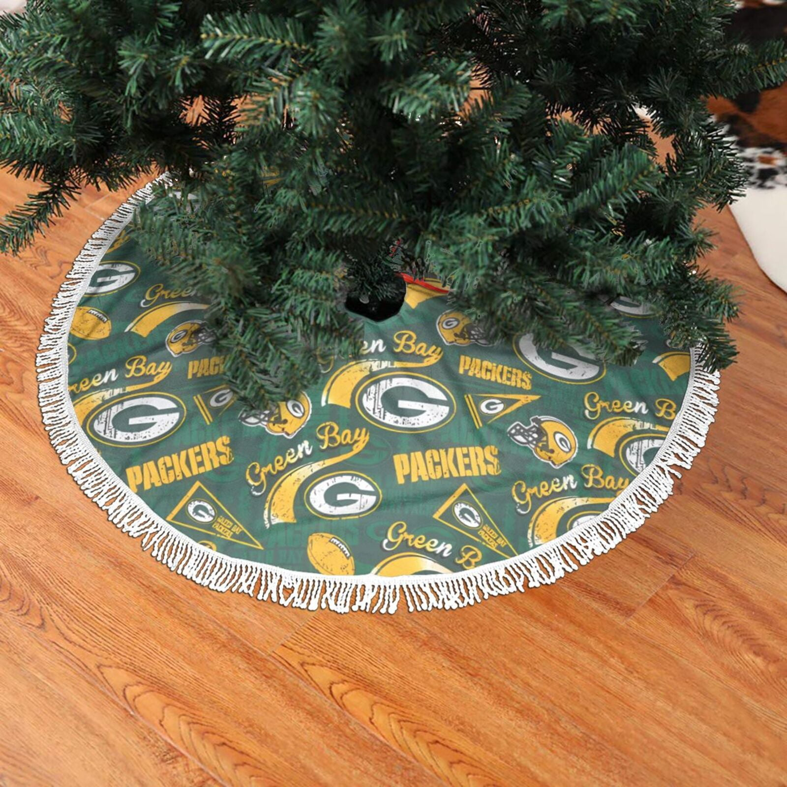 Eine Weihnachtsbaumdecke mit dem Logo der Green Bay Packers. Sie ist grün mit weißem Fransen, auf einem Holzboden.