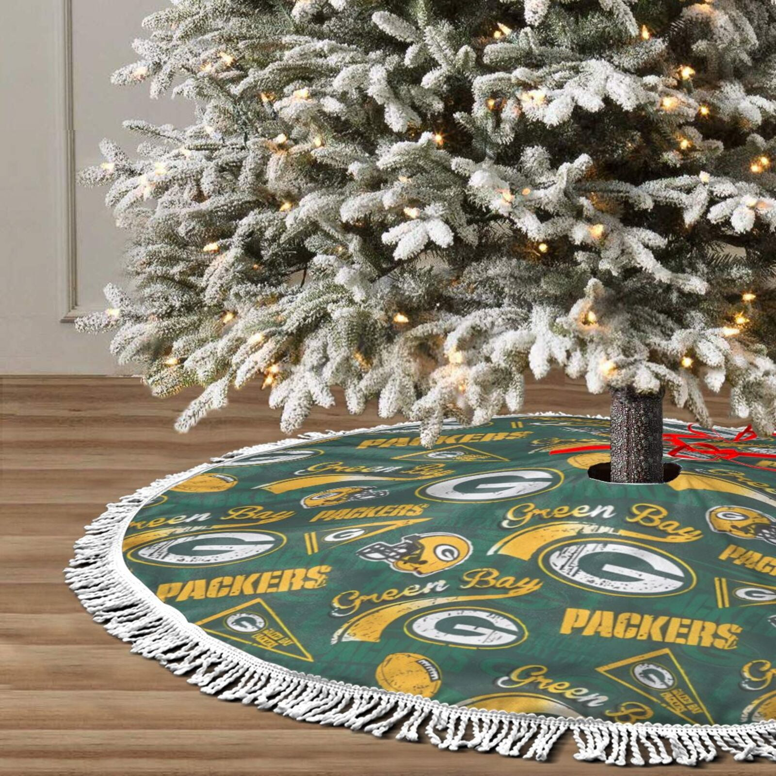Ein geschmückter Weihnachtsbaum mit einem Green Bay Packers-Baumrock. Der Baum ist schneebedeckt und mit Lichtern versehen.