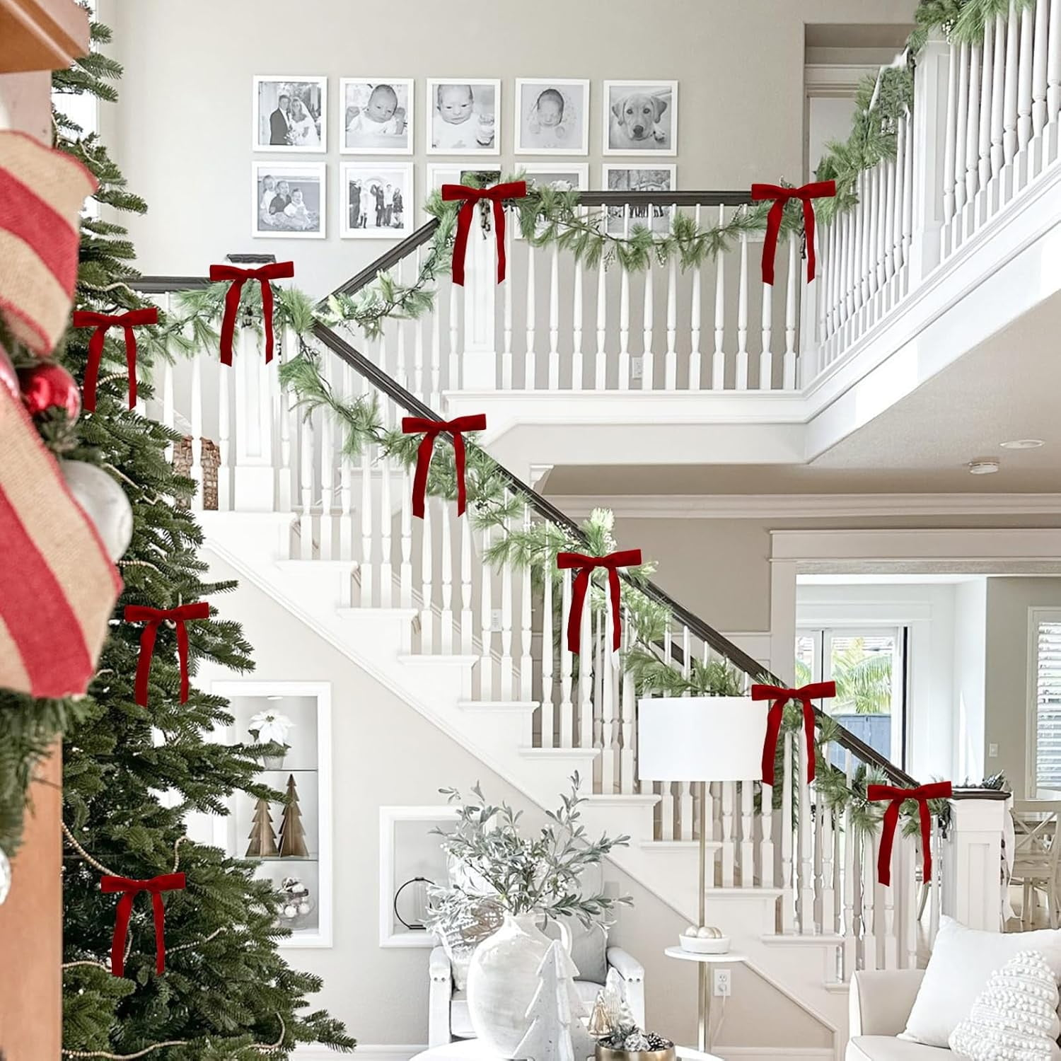 Weihnachtsszene. Treppe mit Girlanden und roten Schleifen geschmückt. Ein Weihnachtsbaum links. Familienfotos an der Wand.