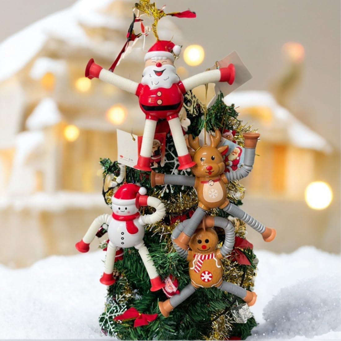 Ein Weihnachtsbaum mit Dekorationen von Weihnachtsmann, Rentier, Schneemann und Lebkuchenmann. Auf verschneiter Oberfläche mit unscharfem Hintergrund.