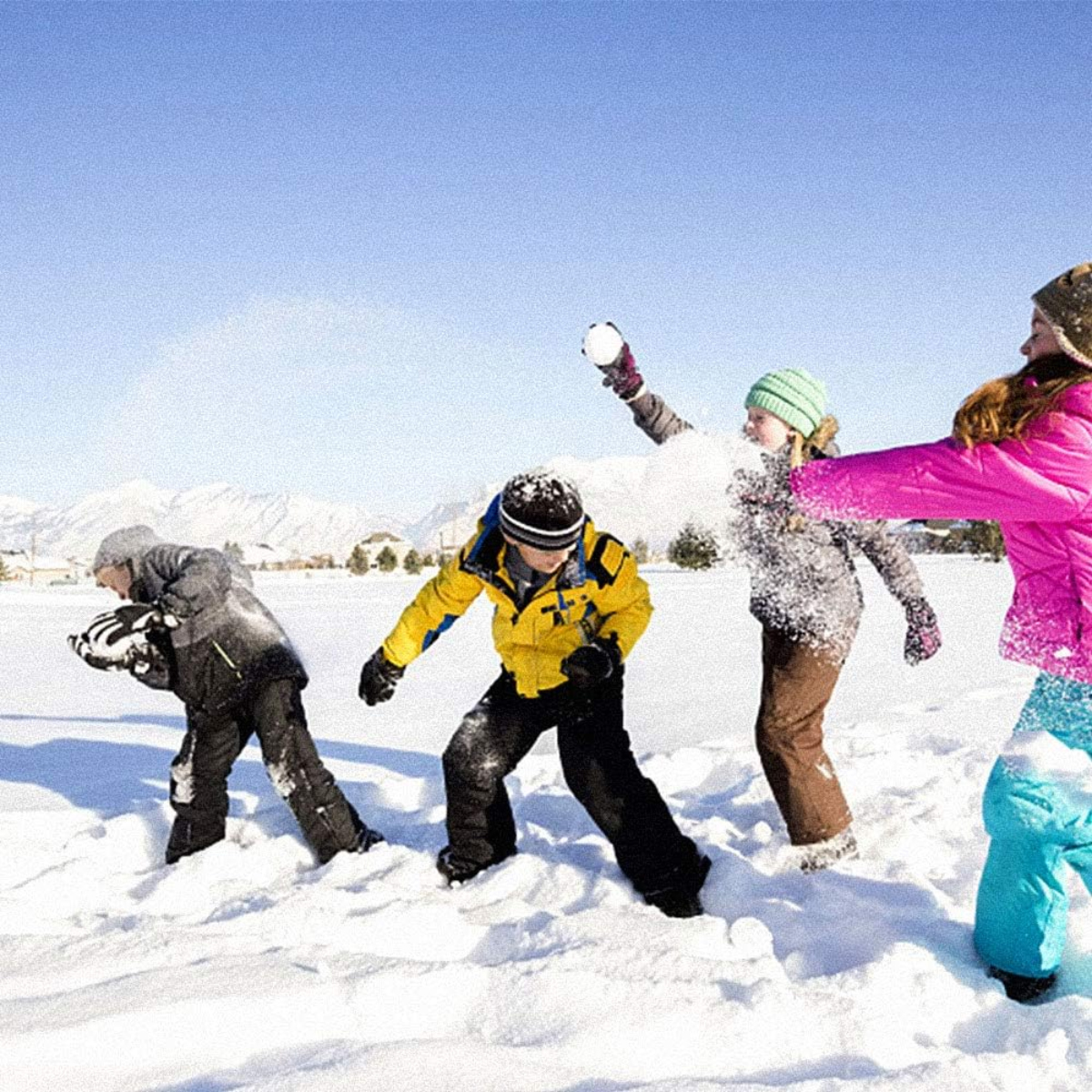 Vier Kinder in Winterkleidung spielen im Schnee. Einer wirft einen Schneeball. Berge und Himmel sind im Hintergrund.