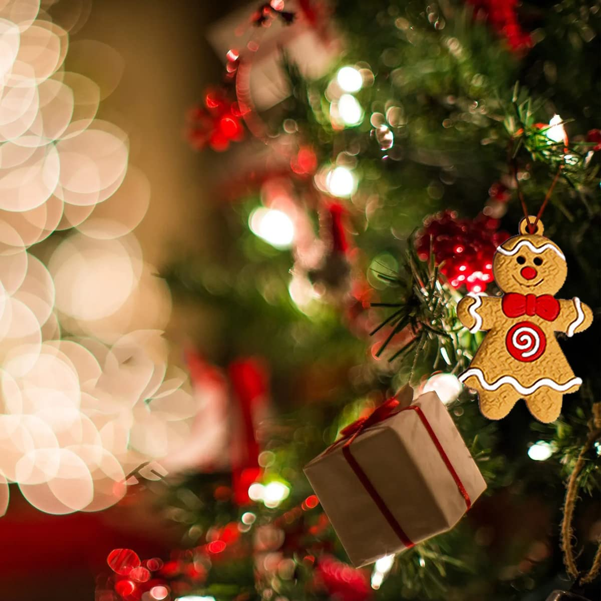 Ein Weihnachtsbaum mit einem Lebkuchenmann-Ornament und einer Geschenkbox. Warme Bokeh-Lichter im Hintergrund.