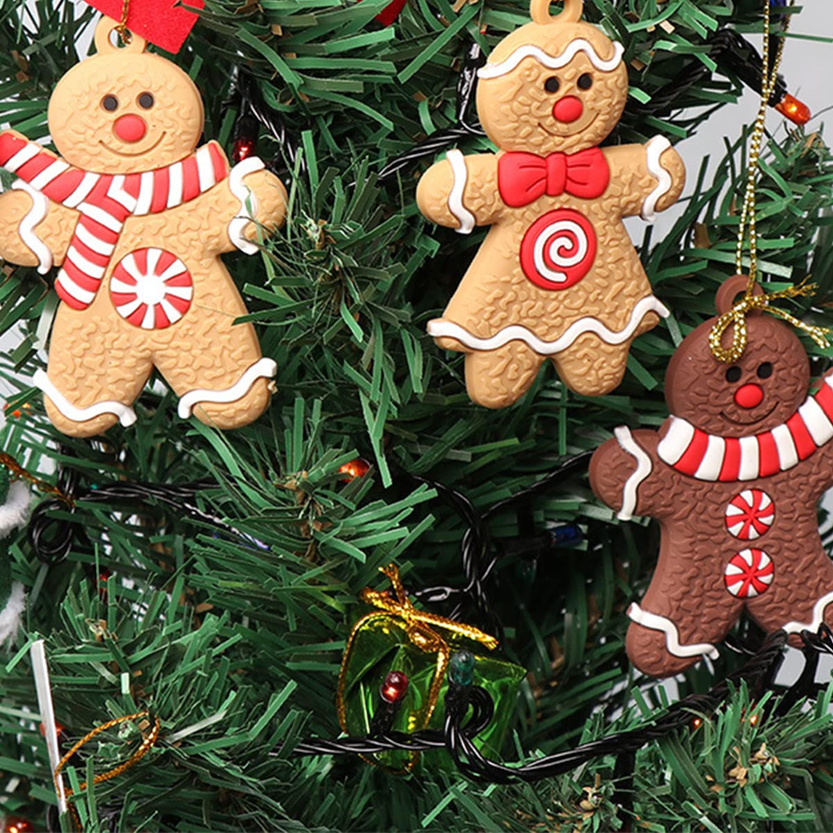 Weihnachtsbaum mit Lebkuchenmann-Ornamenten. Einer hat einen Schal, ein anderer eine Fliege. Eine grüne Geschenkbox ist ebenfalls sichtbar.