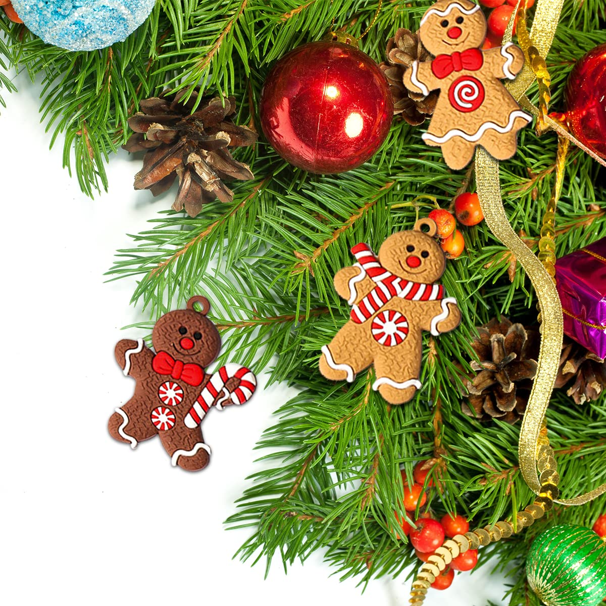 Weihnachtsarrangement mit Tannenzweigen, Lebkuchenmännern, roten Ornamenten, Tannenzapfen und Beeren, vor weißem Hintergrund.