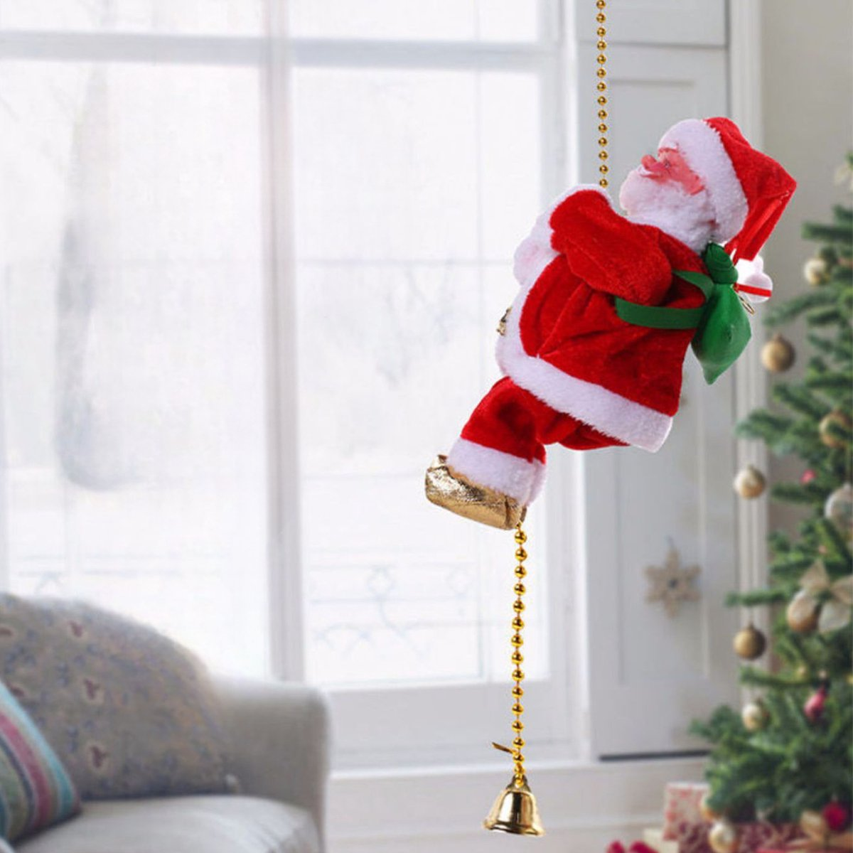 Eine Weihnachtsmann-Dekoration klettert an einem goldperlenbesetzten Seil. Ein Weihnachtsbaum und ein Fenster sind im Hintergrund.