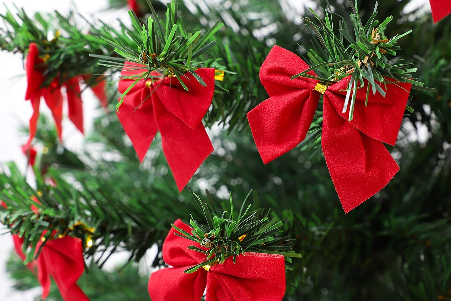Nahaufnahme eines Weihnachtsbaums mit leuchtend roten Schleifen. Grüne Nadeln bilden den Hintergrund und die Schleifen sind im Vordergrund.