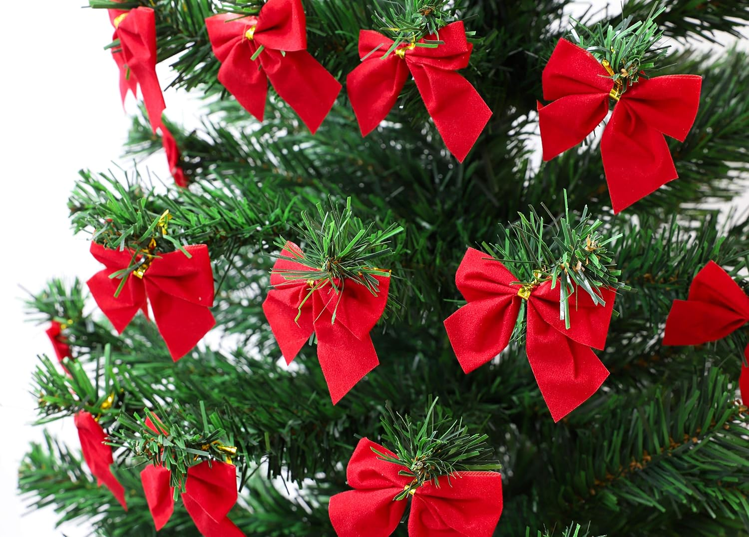 Nahaufnahme eines Weihnachtsbaums mit roten Schleifen. Grüne Nadeln füllen den Rahmen, mit Schleifen unterschiedlicher Größe.