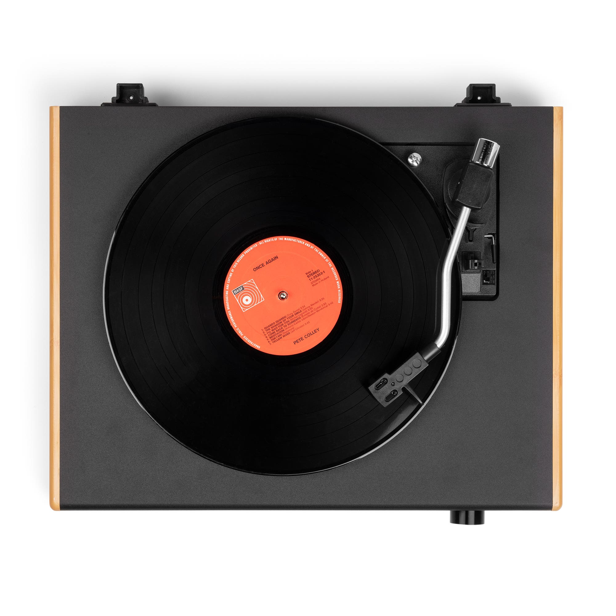 Un tocadiscos con un disco negro reproduciéndose. La etiqueta del disco es naranja. El tocadiscos es negro y de madera.