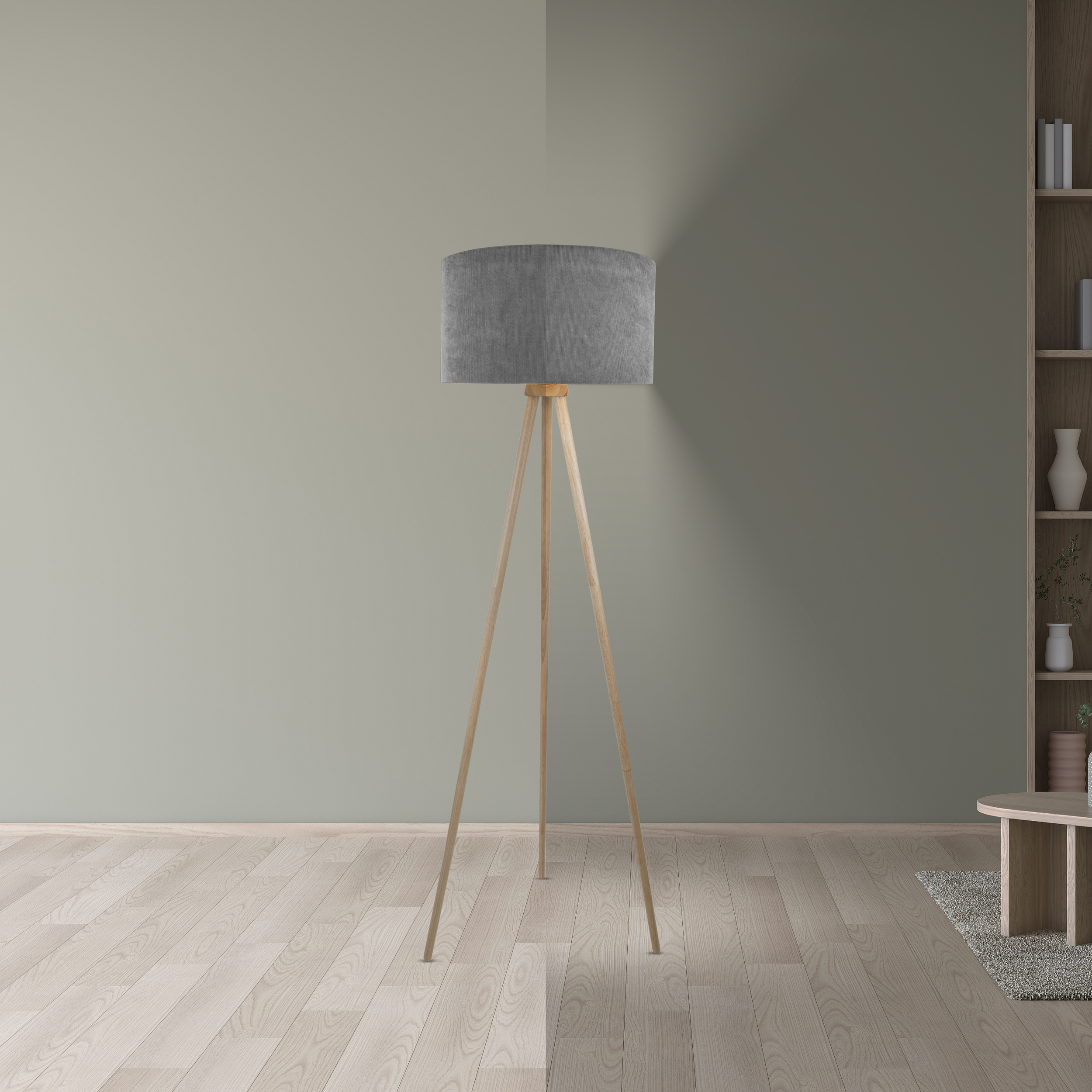 Eine graue Lampe mit Holzbeinen steht vor einer grünen Wand. Rechts ist ein Regal mit Dekoration.