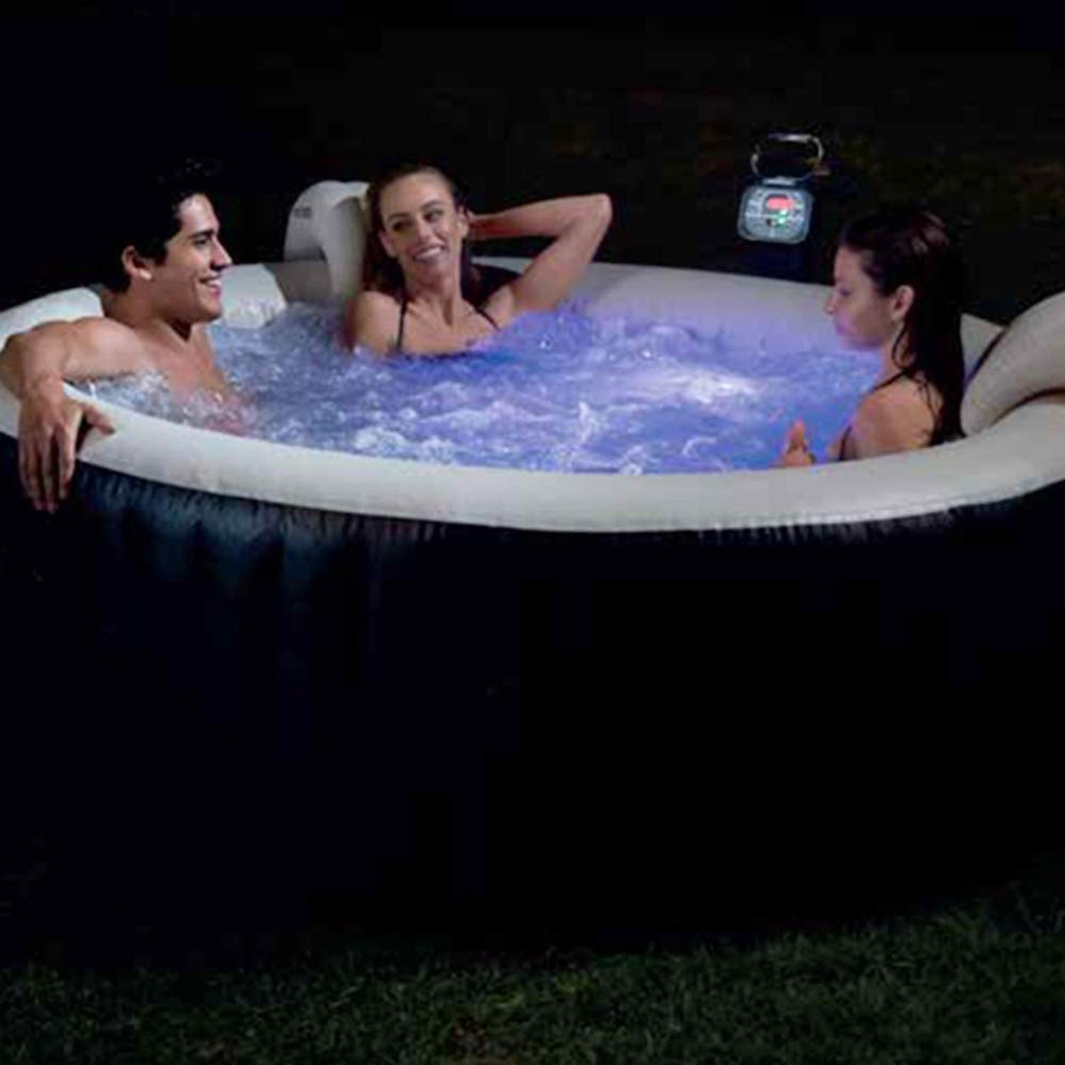 Tres personas se relajan en un jacuzzi por la noche. El agua está iluminada con luz azul, y sonríen y se divierten.