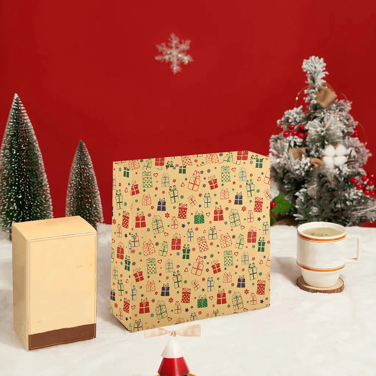 Festliche Szene mit Geschenken, Minibäumen und einer Schneeflocke vor rotem Hintergrund. Eine Tasse steht auf einem Untersetzer.
