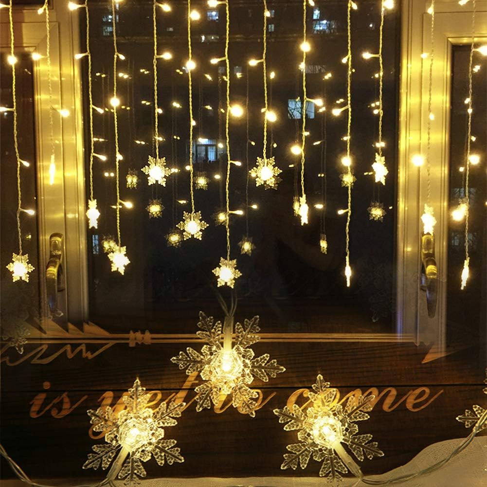 Fenster mit Schneeflockenlichtern. Warme gelbe Lichter hängen wie Eiszapfen. Schneeflockenlichter sind am Fenster, der Hintergrund ist dunkel.