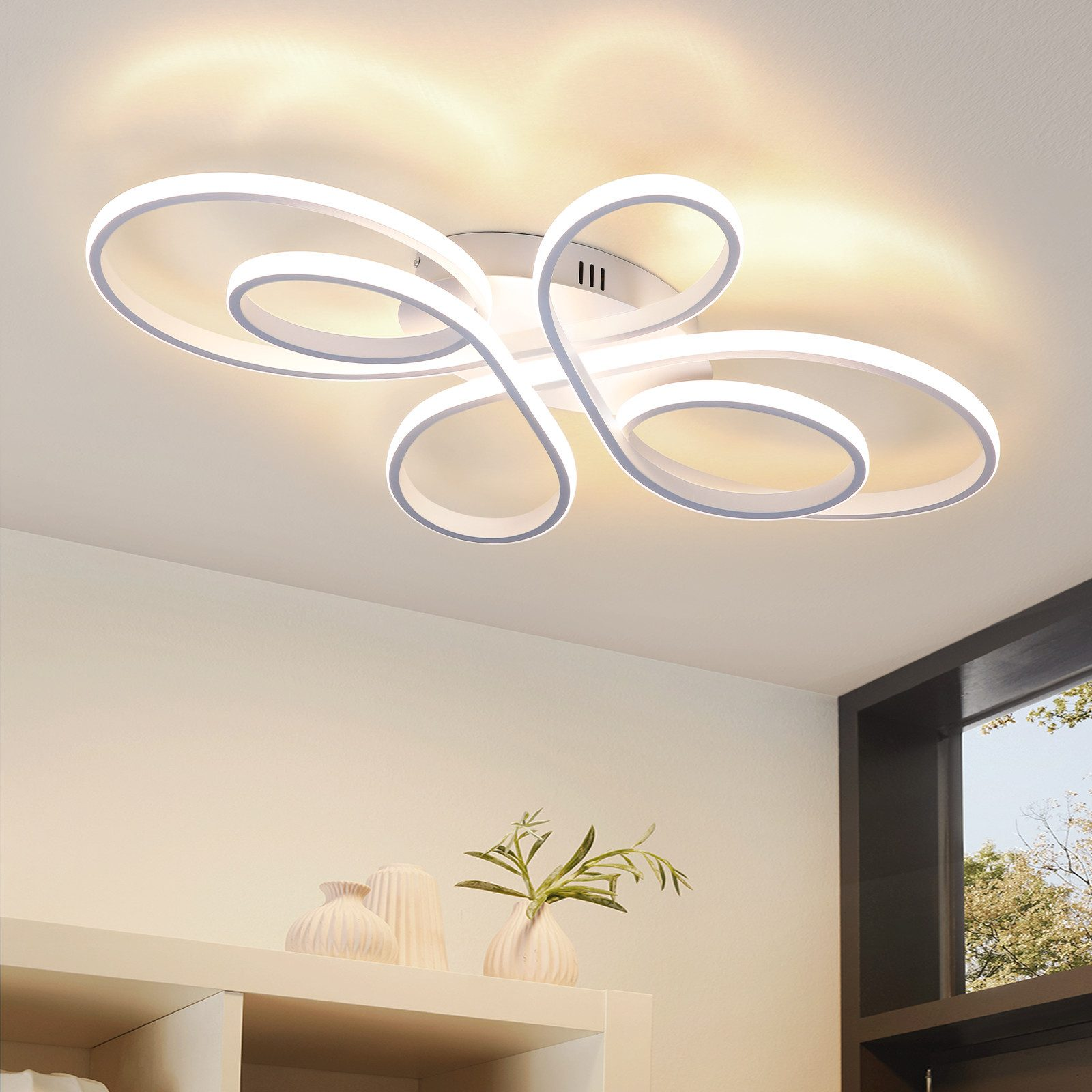Una moderna lampada da soffitto con un design unico e a spirale. Sotto, una mensola con vasi e una pianta. Una finestra rivela un albero.