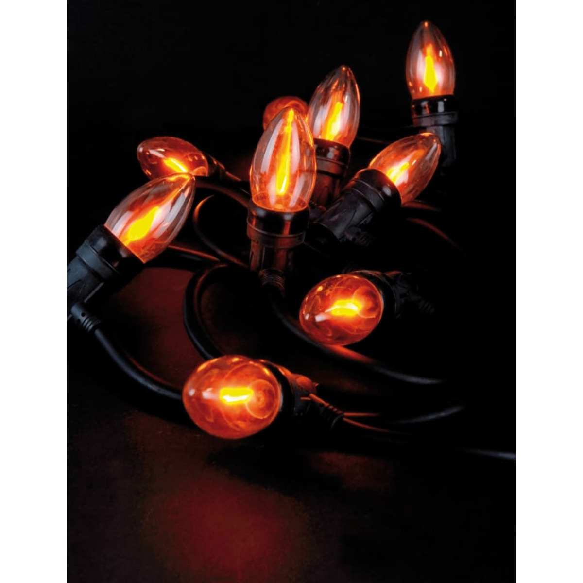 Nahaufnahme von Lichterketten mit orangefarbenen Glühbirnen auf schwarzem Hintergrund. Die Glühbirnen leuchten, die Drähte sind dunkel.