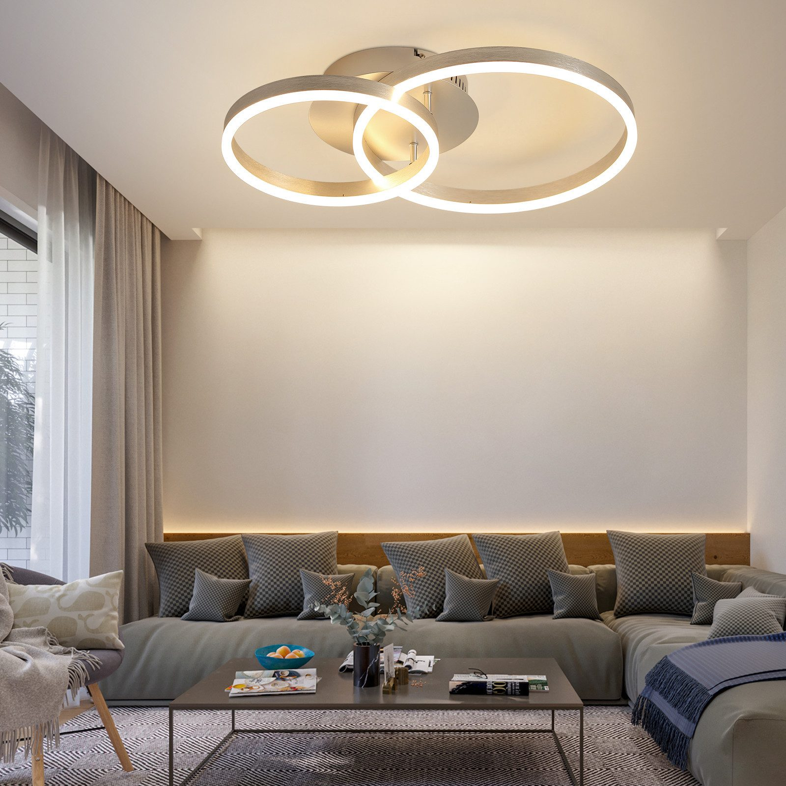Soggiorno con un moderno lampadario. Sono visibili un divano con cuscini, un tavolino e una finestra.