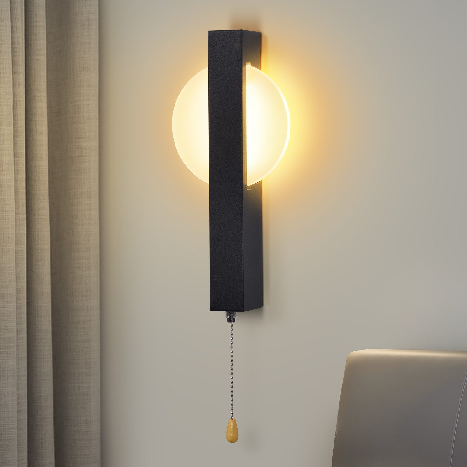 Eine moderne Wandlampe mit schwarzem Rahmen und rundem Licht. Hängt an einer beigen Wand neben einem Vorhang.