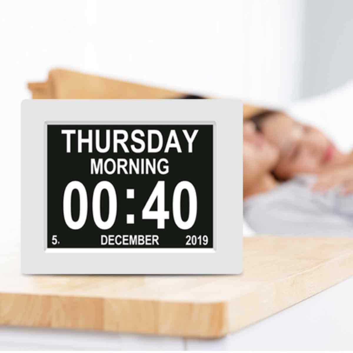 Digitaluhr zeigt Donnerstagmorgen, 00:40 Uhr, 5. Dezember 2019. Verschwommen schlafende Personen im Hintergrund auf Holzoberfläche.