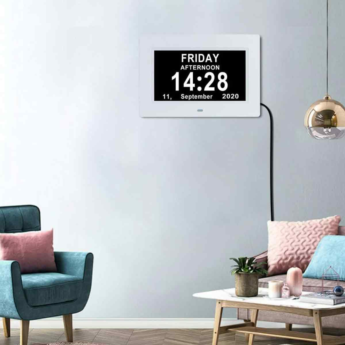 Eine Digitaluhr zeigt Freitagnachmittag, 14:28 Uhr, 11. September 2020 an. Ein türkisfarbener Stuhl und rosa Kissen sind im Raum.