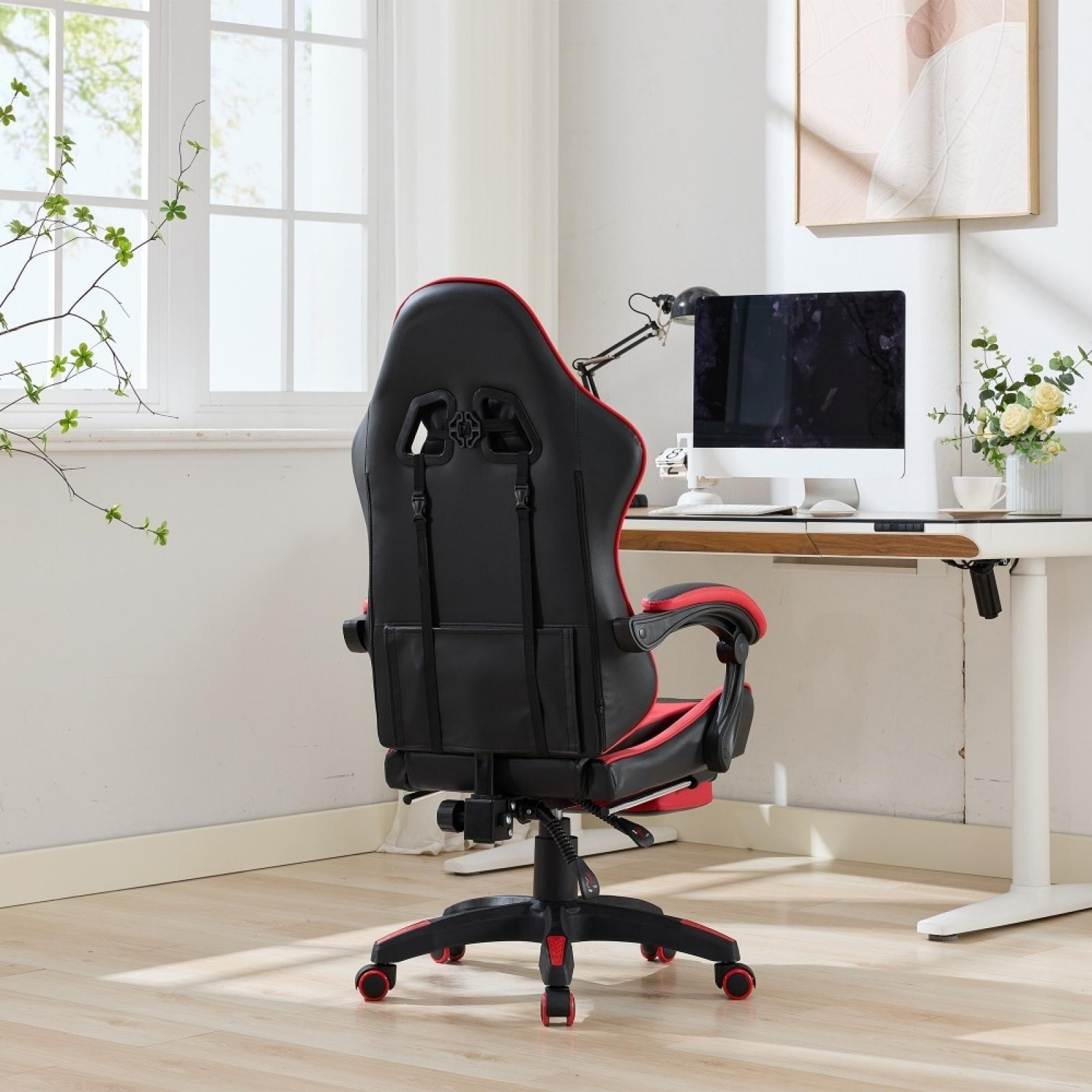 Schwarzer und roter Gaming-Stuhl. Schreibtisch mit Computer, Lampe und Blumen im Hintergrund. Fenster links.