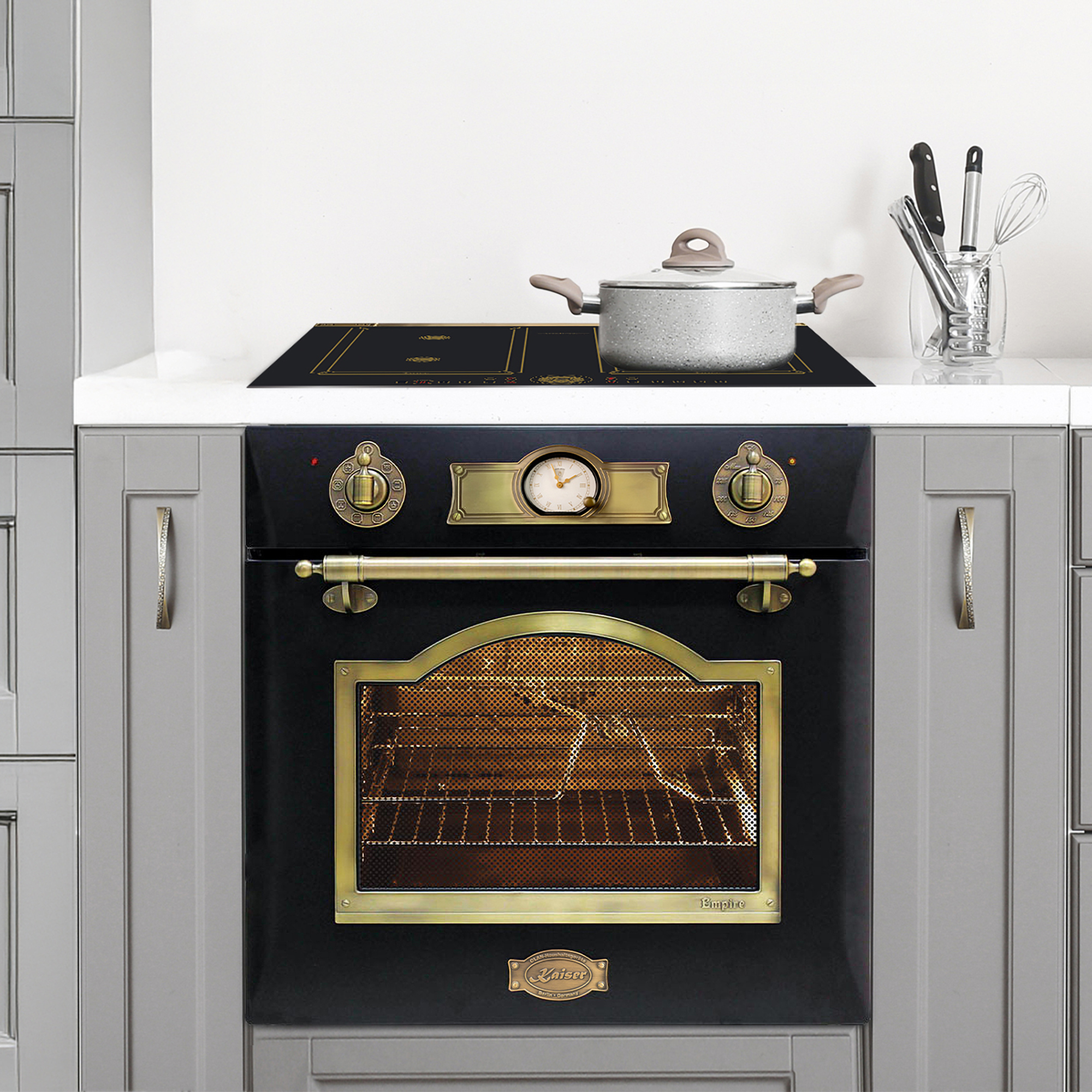 Küchenszene mit Backofen, Herd und Topf. Der Ofen ist schwarz mit goldenen Akzenten. Graue Schränke sind beidseitig.