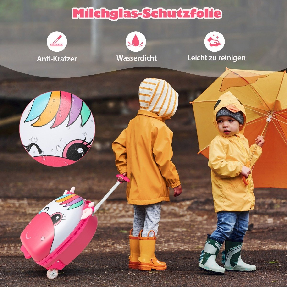 Dos niños con impermeables y botas, uno con paraguas. Una maleta con diseño de unicornio está en primer plano.
