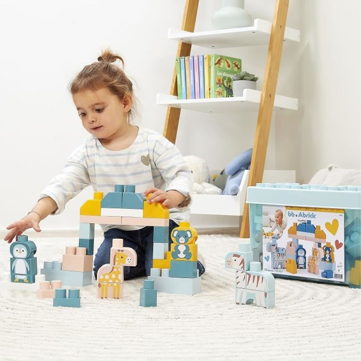 Una bambina gioca con blocchi di costruzione a forma di animali. I blocchi sono blu, gialli e rosa. Un contenitore è sullo sfondo.