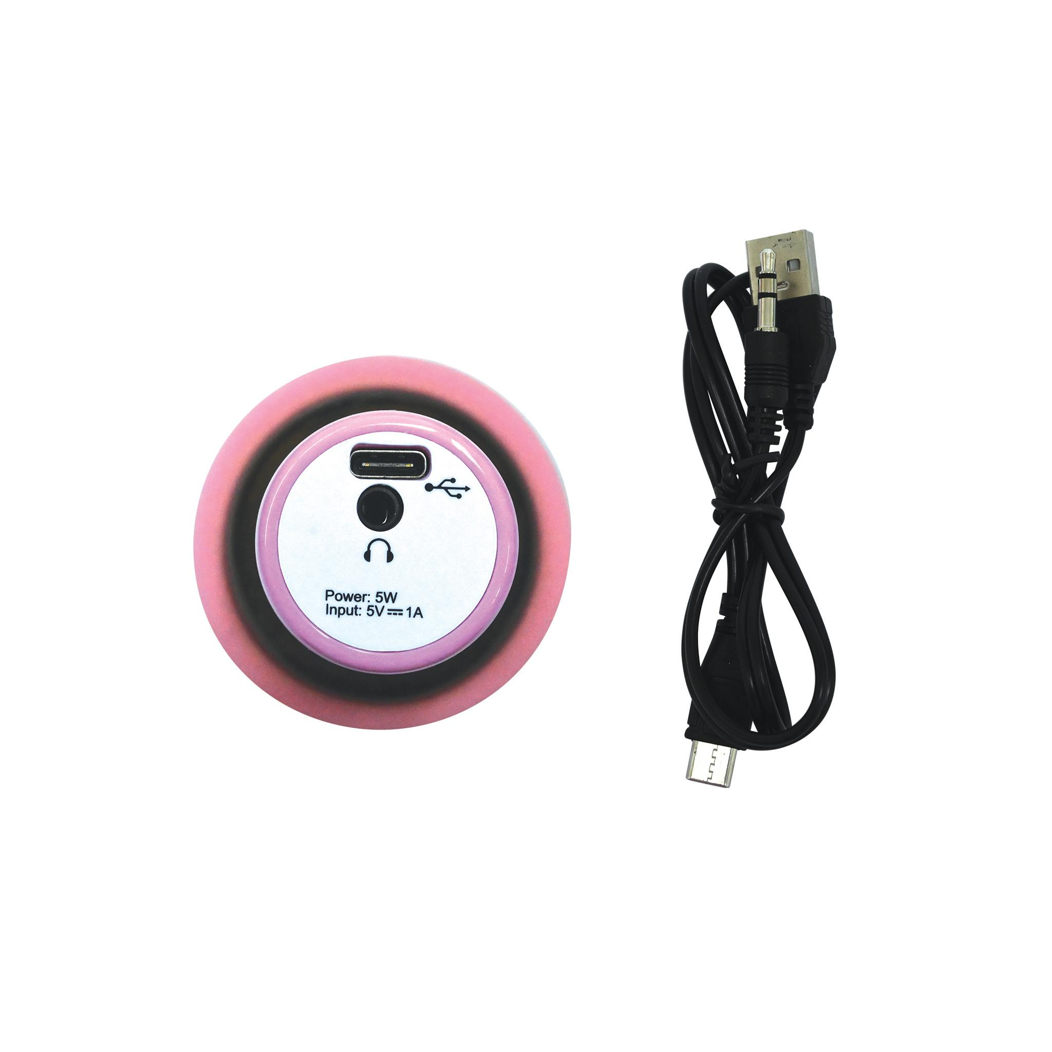 Un dispositivo rotondo rosa e bianco con un cavo nero. Il dispositivo ha una porta USB e un'icona delle cuffie. Sfondo bianco.