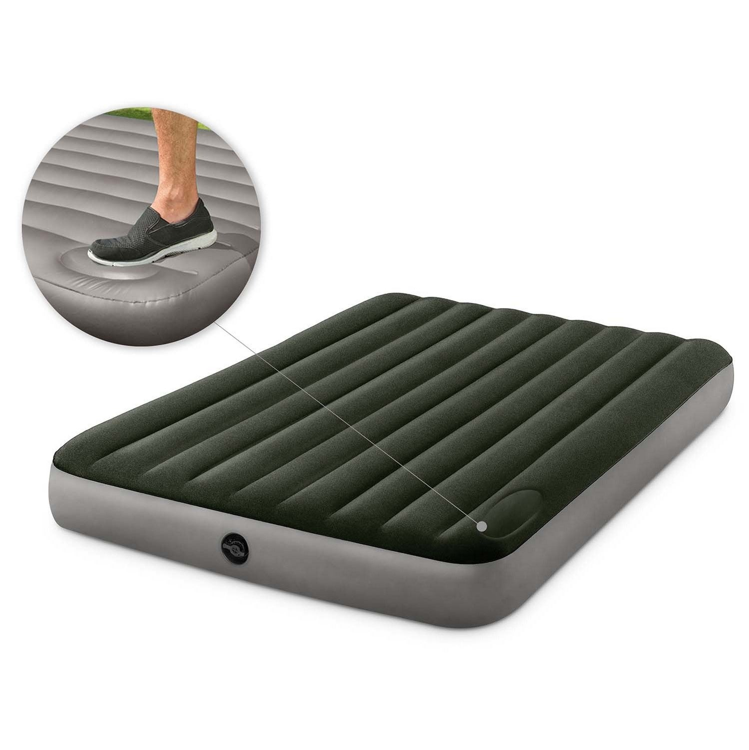 Una cama inflable, con la parte superior verde oscuro y los lados grises, con un primer plano de un pie pisando la cama.