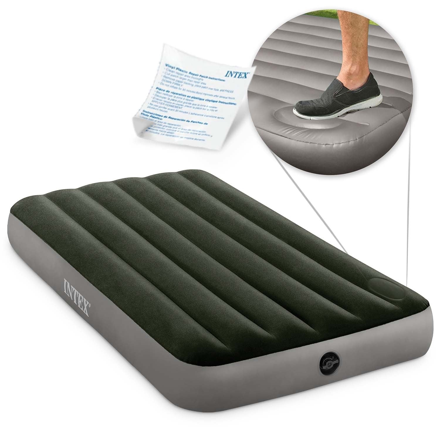 Un colchón de aire Intex, con el pie de una persona con un zapato encima. Hay instrucciones de parche de reparación cerca. El colchón es gris y negro.