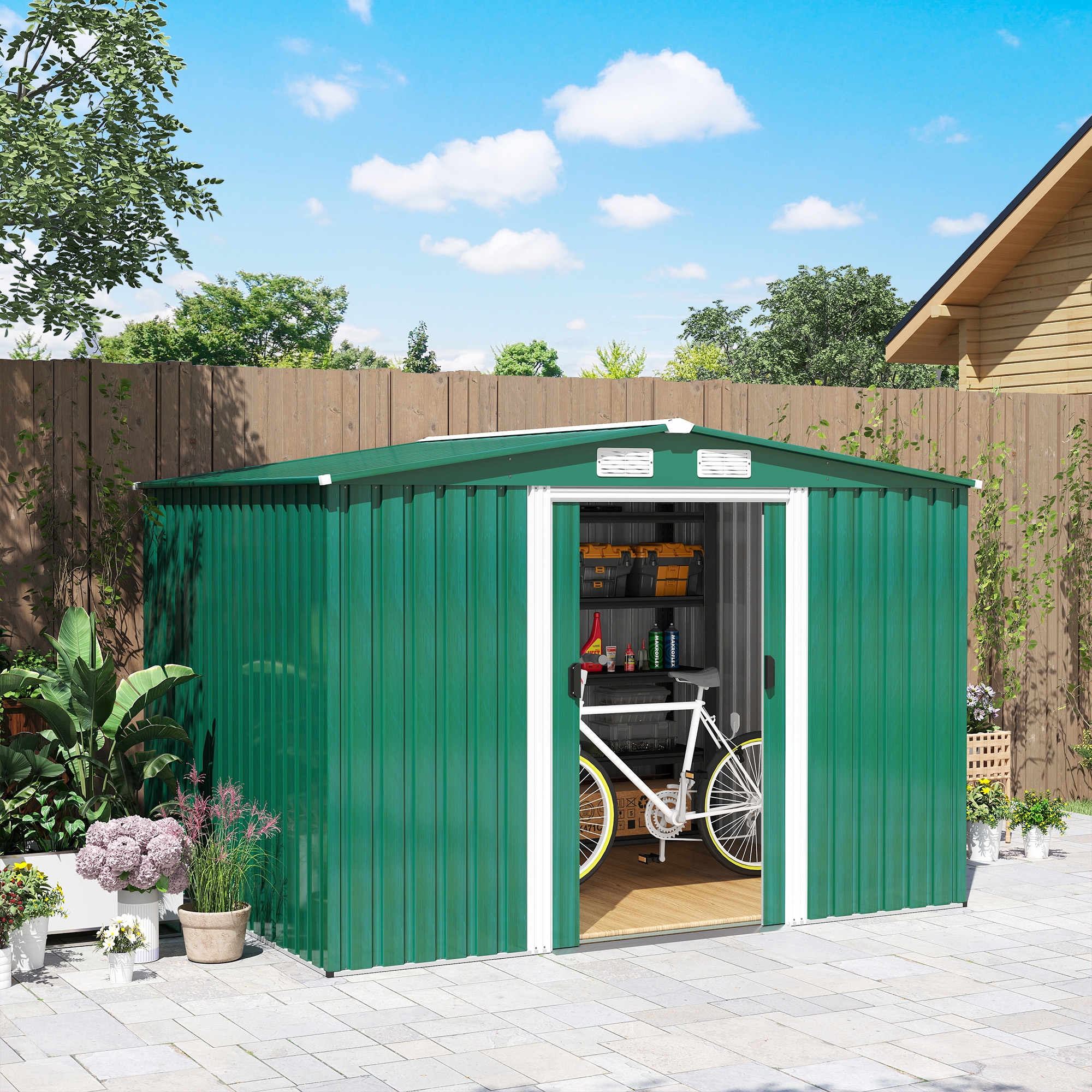 Capanno verde con porta aperta, bicicletta visibile. Fiori e piante, recinzione in legno e cielo blu sullo sfondo.