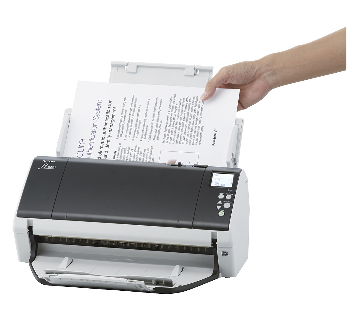 Ręka wkładająca papier do skanera Ricoh fi-7480. Papier zawiera tekst o uwierzytelnianiu biometrycznym.