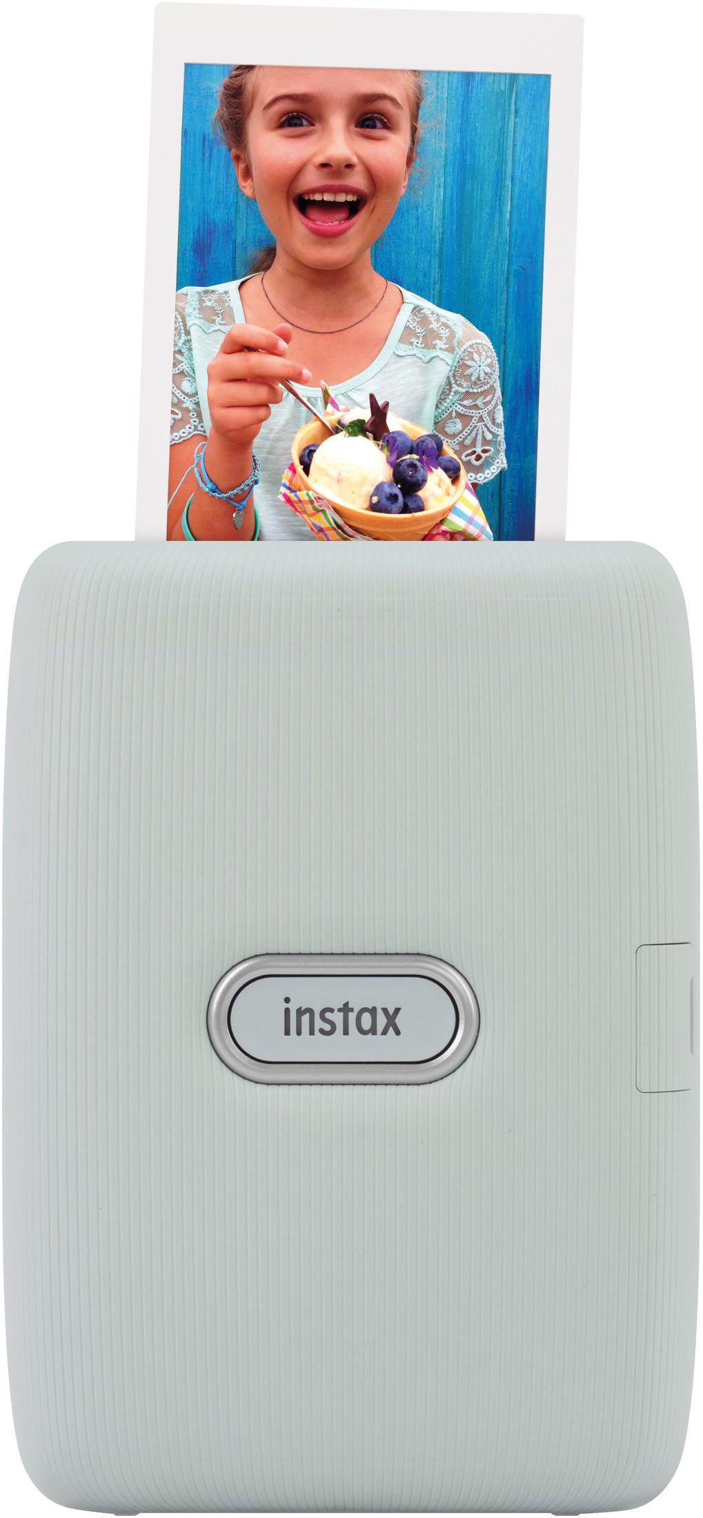 Dziewczyna trzyma zdjęcie lodów. Drukarka poniżej ma napis 'instax'.