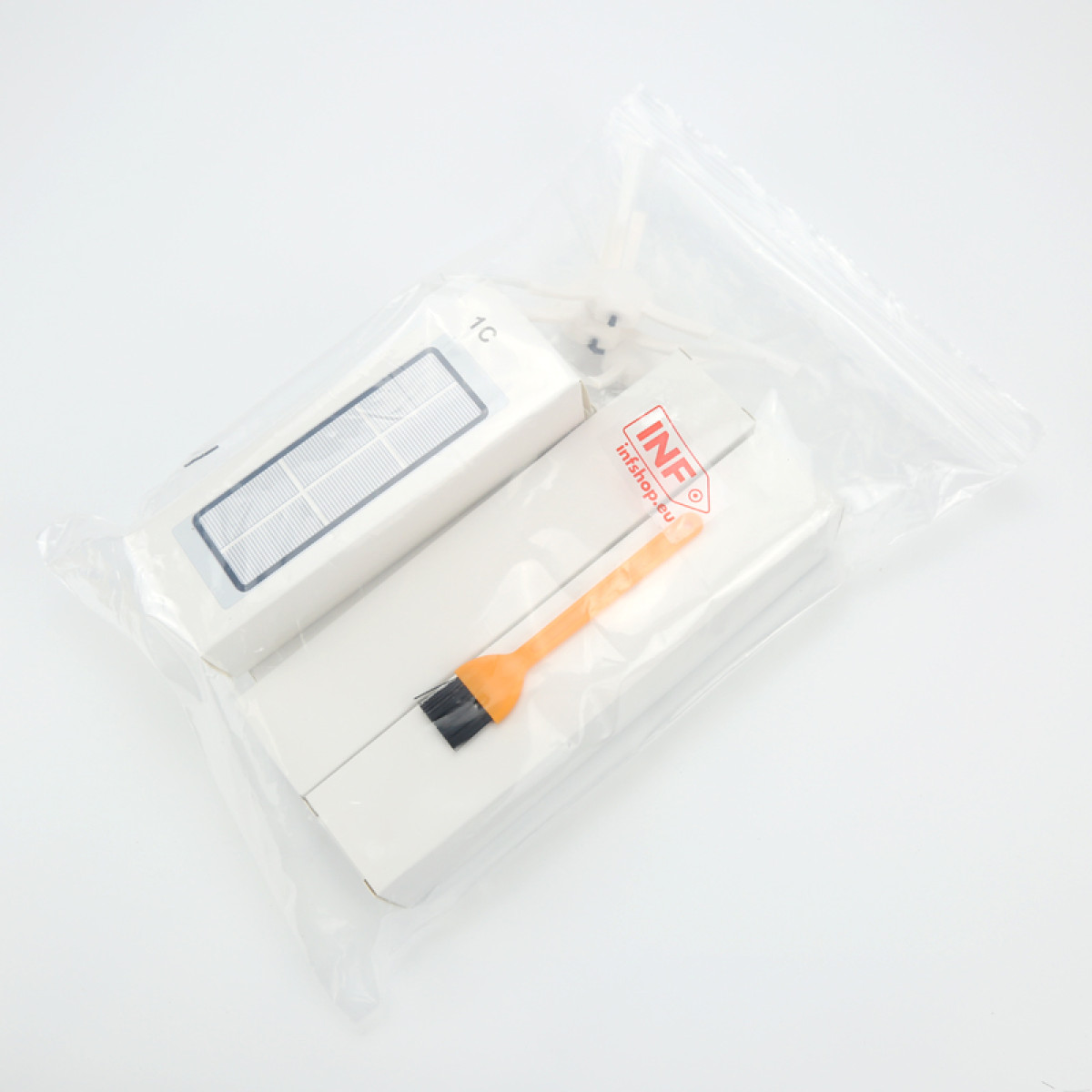 Zamknięta torba z białymi pudełkami, jedno z napisem 1C, drugie z pomarańczową szczotką. Tło białe.