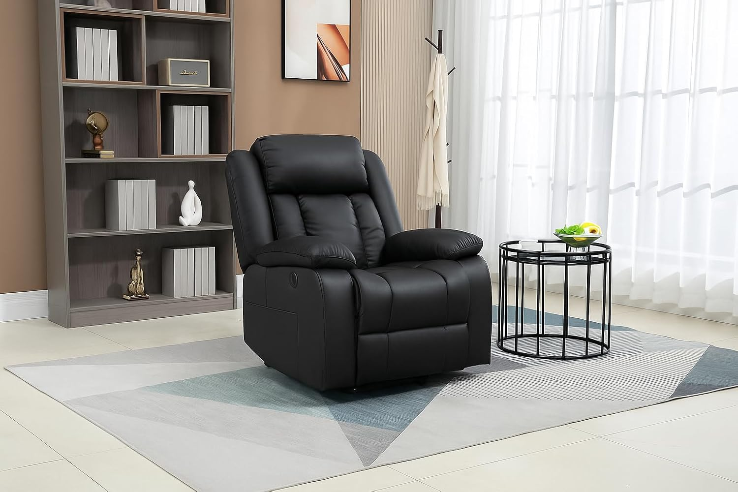 Un sillón reclinable de cuero negro en una habitación con una estantería, una mesita con fruta y una alfombra con patrones geométricos.