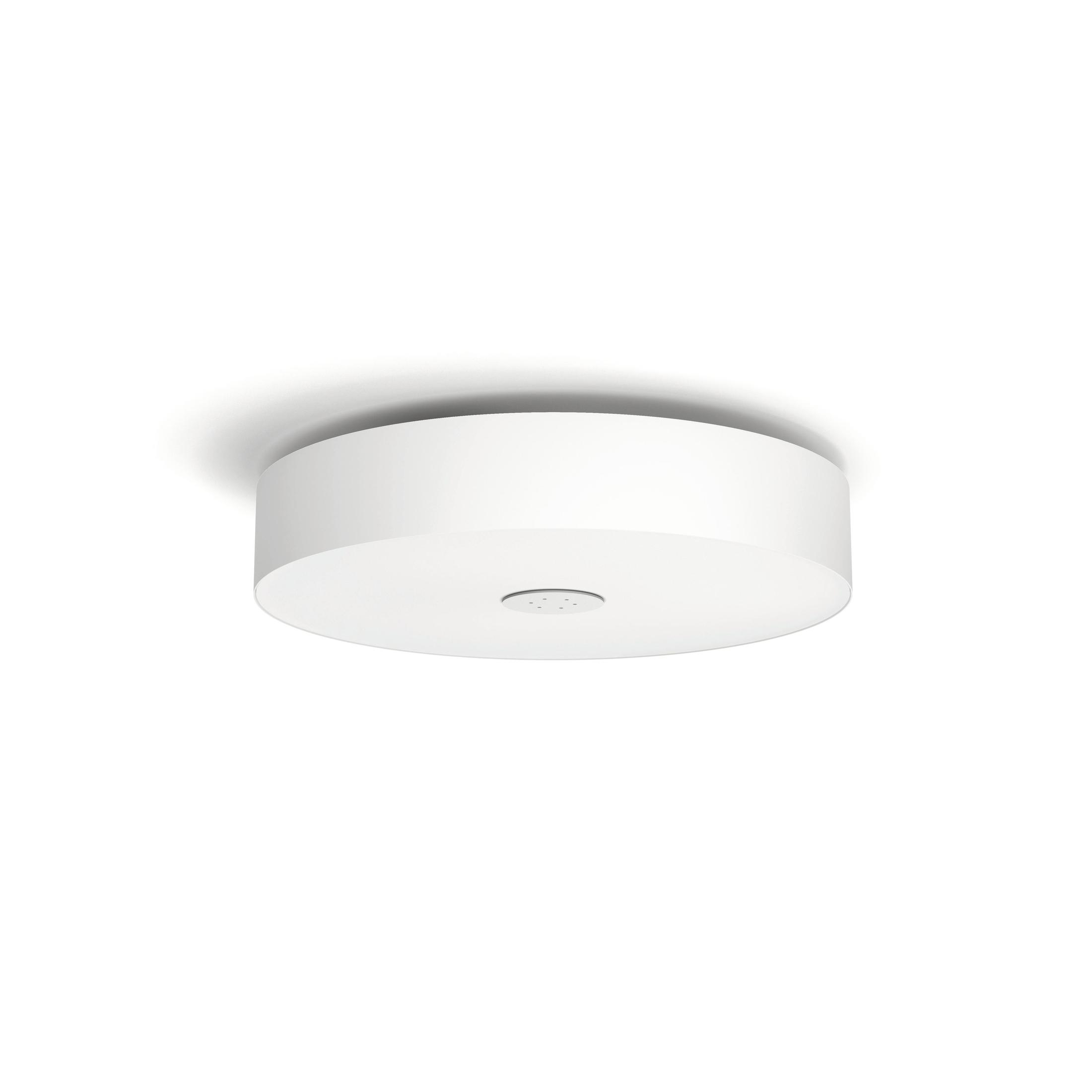 Un plafonnier blanc et circulaire. Il projette une ombre douce sur le plafond blanc. La pièce est bien éclairée.